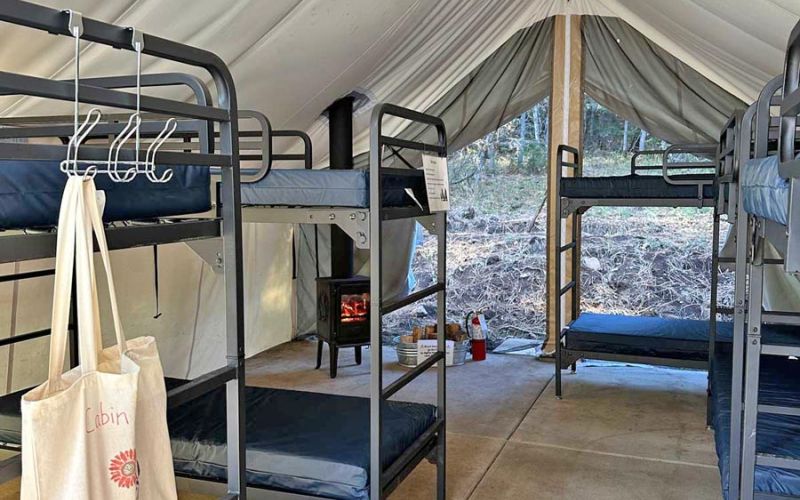 inside ADA-accessible wall tent are bunk beds and wood stove