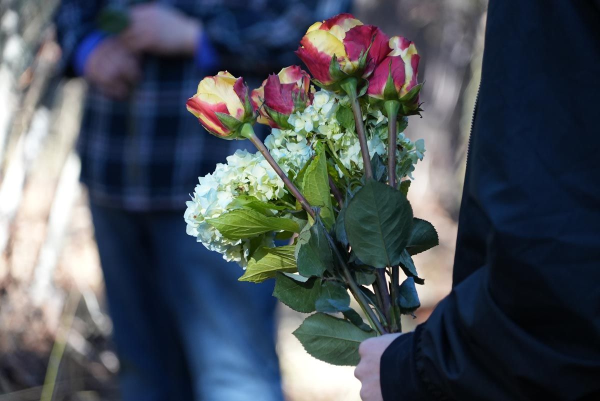closeup of mourner holding a flower bouquet at green burial ceremony at The Forest Conservation Burial Ground at Willow-Witt Ranch