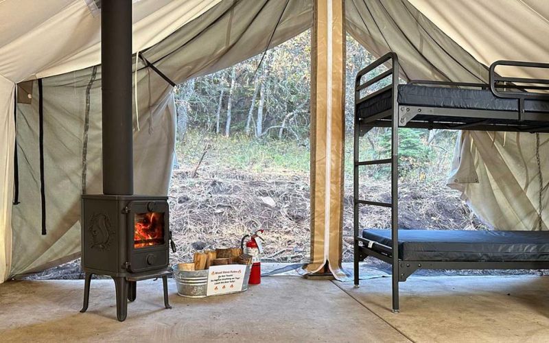 accessible group wall tents have bunk beds and wood stoves in forest setting