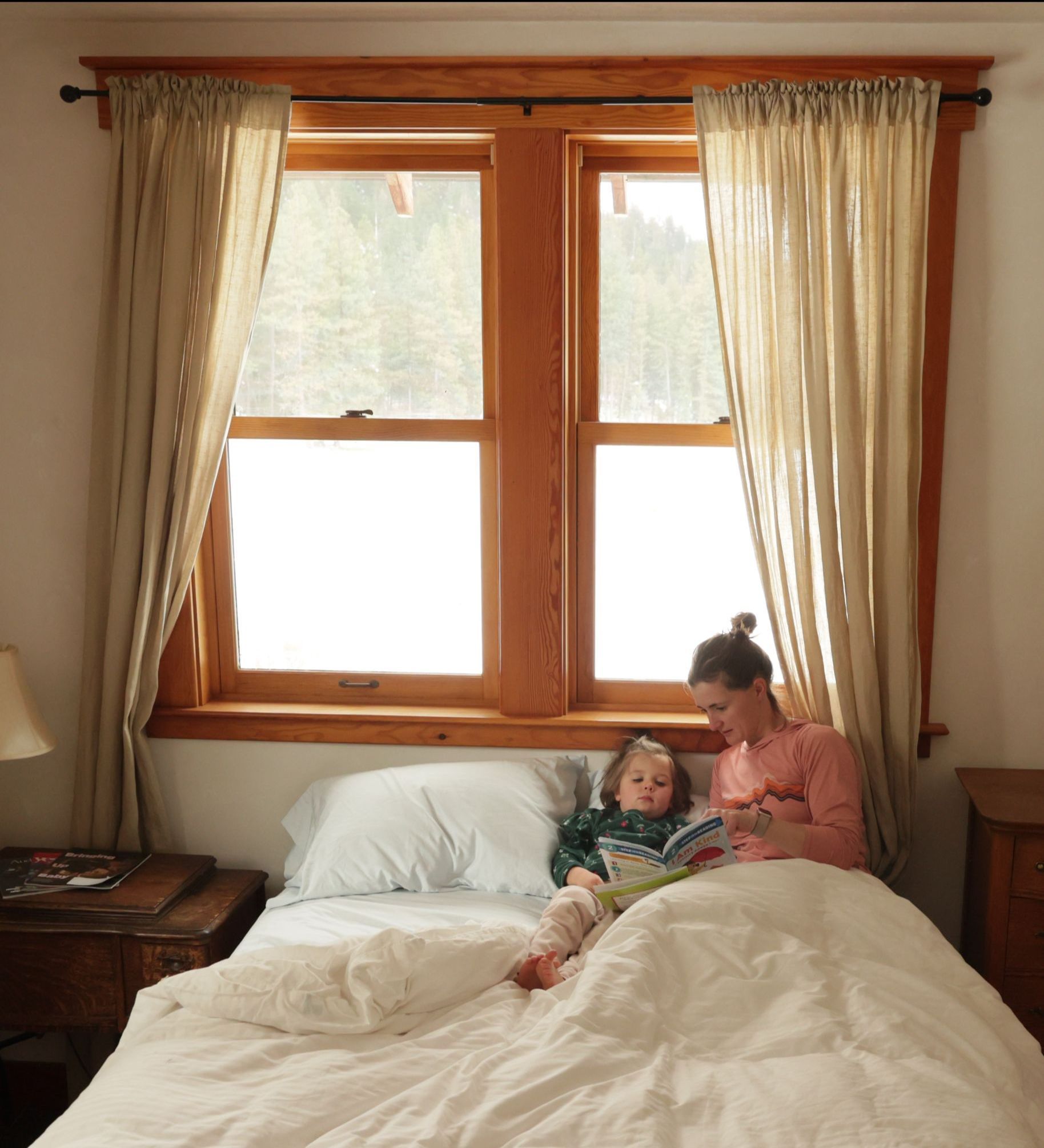 mother reads to young daughter in bed during winter farm stay at the Meadow House