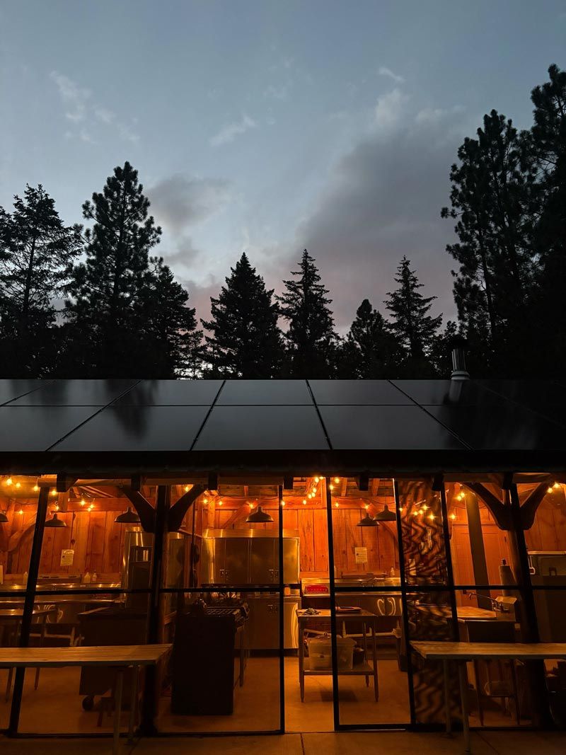 screened campground cookhouse lit up with string lights for glowing ambiance at dusk