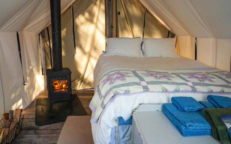 Inside Raven wall tent with double bed and wood stove