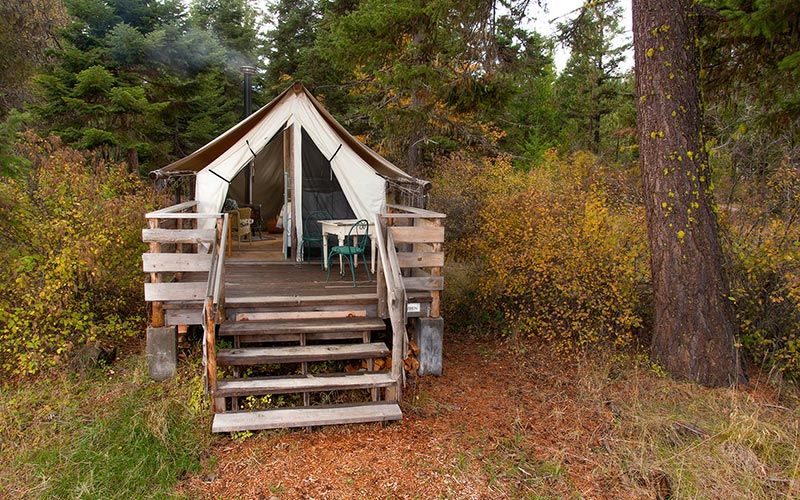 Wren wall tent with queen bed, wood stove, and front deck with table and chairs